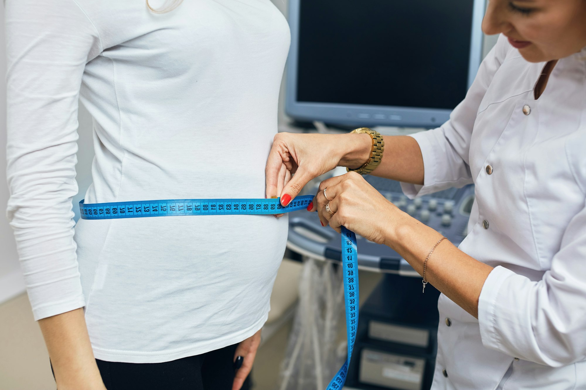 nurse using the ribbon to measure the size of a belly